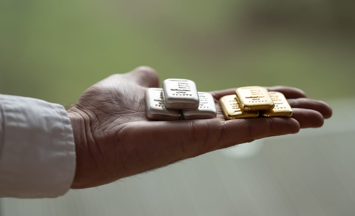 A hand holding small gold and silver bars