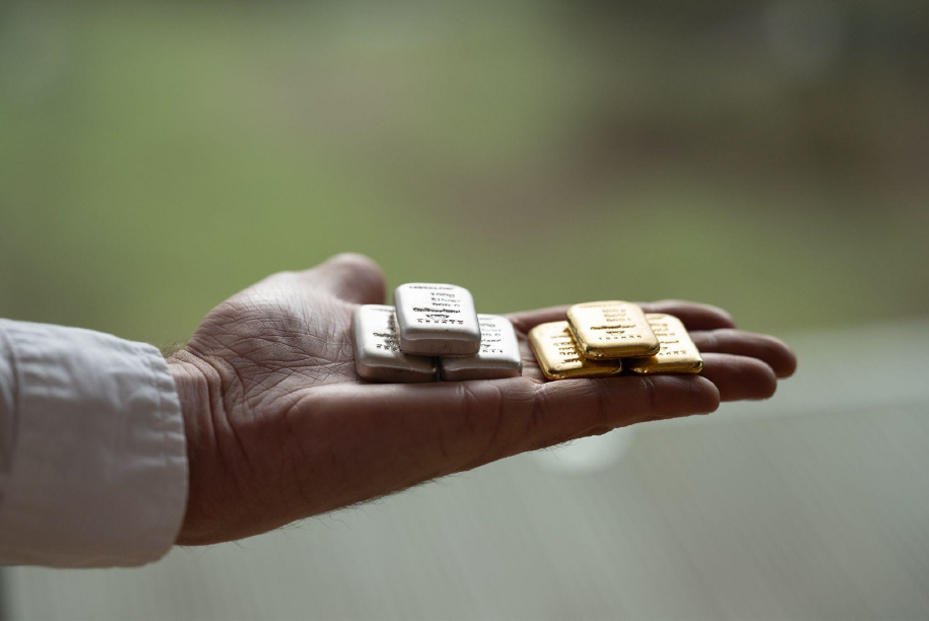 A hand holding small gold and silver bars