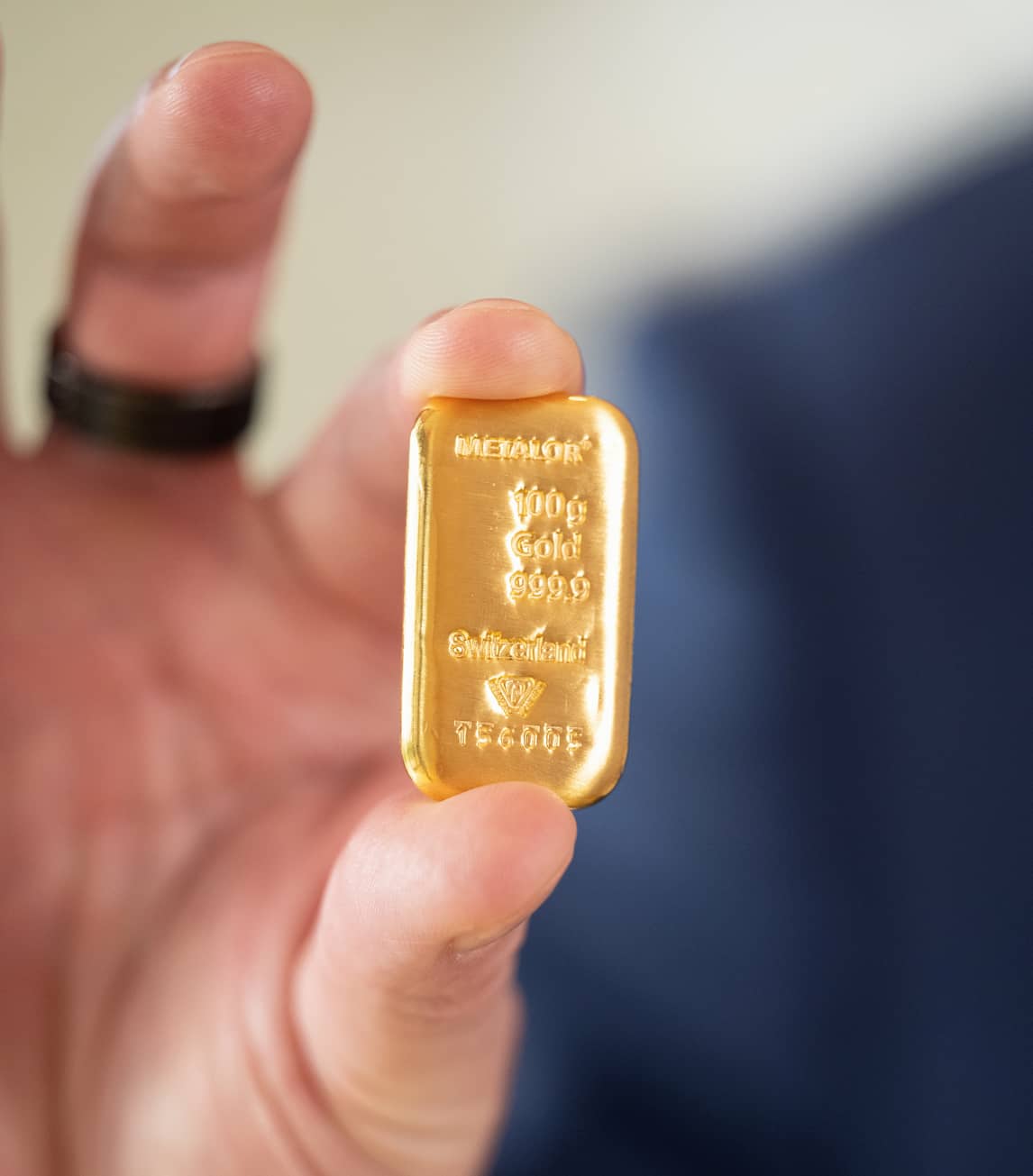 A small gold bar held between finger and thumb